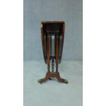 A Regency style mahogany oval drop flap dining table on brass lion paw feet. H.74cm W.138cm D.99cm