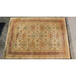A Persian style rug with repeating floral motifs on a yellow field surrounded by floral and