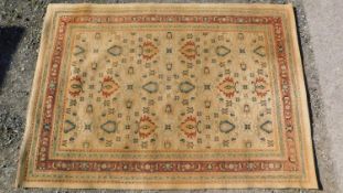 A Persian style rug with repeating floral motifs on a yellow field surrounded by floral and