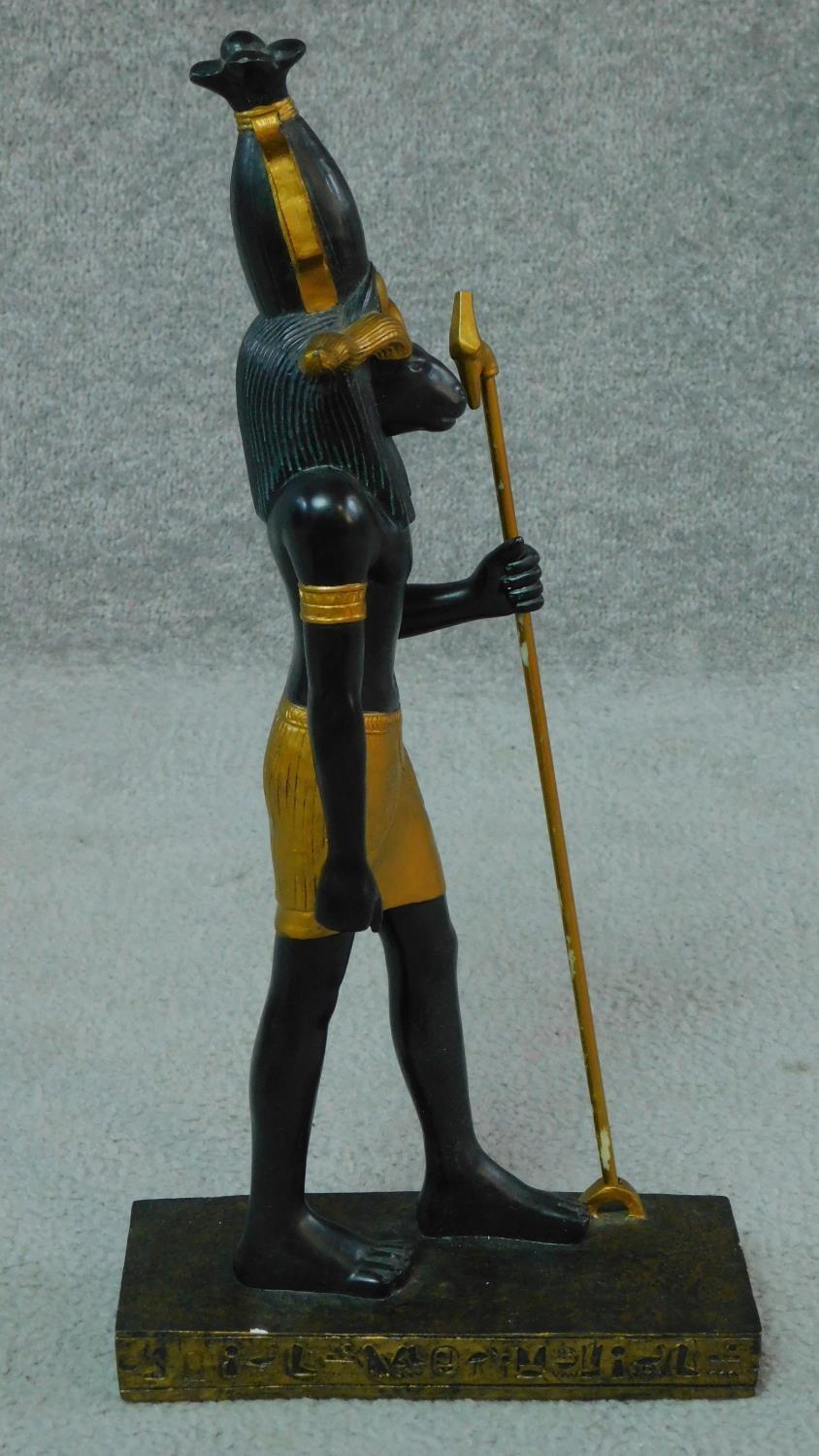 A moulded statue of the Egyptian god Khnum in black and gold with hieroglyphs around the base. H.