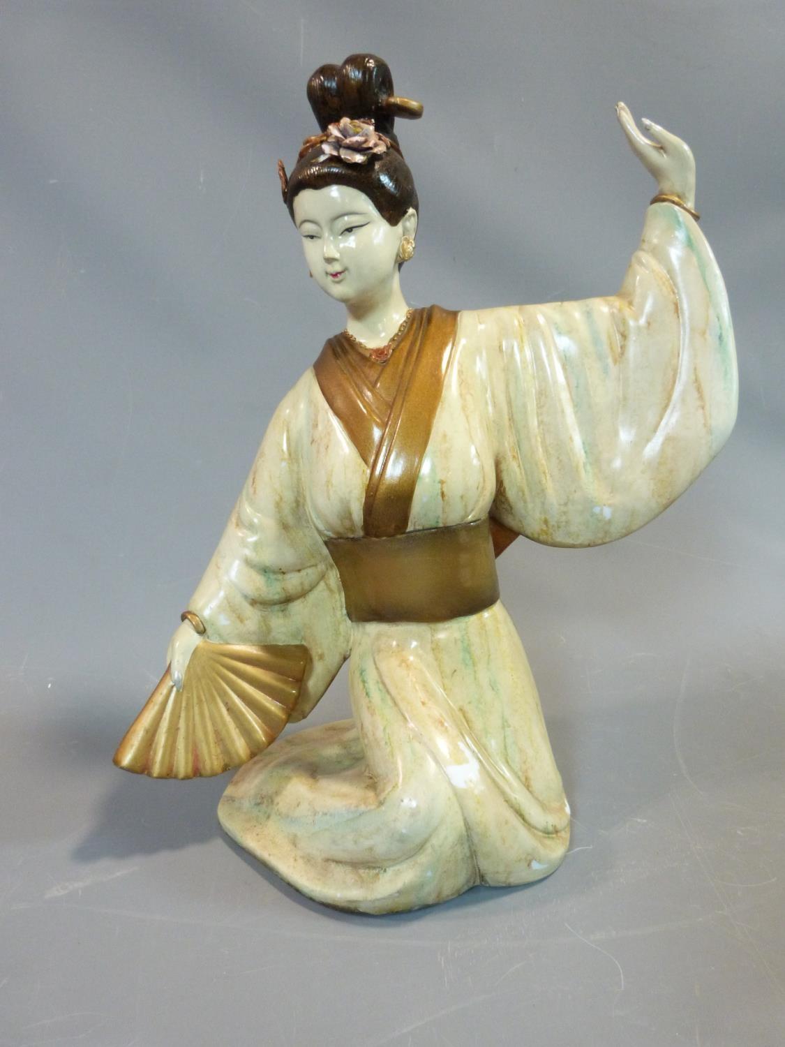 A ceramic figure of a Geisha girl, with fan and flowers in her hair. Gilded decoration. H.45cm.