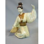 A ceramic figure of a Geisha girl, with fan and flowers in her hair. Gilded decoration. H.45cm.