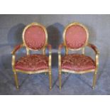 A pair of gilt framed Louis XVl style open armchairs in rouge damask upholstery - H.105 x 56cm