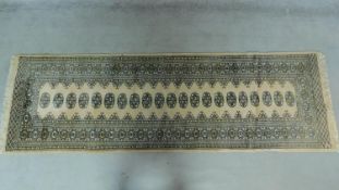 An elephant pad runner set on an ivory field surrounded by repeating stylised borders 153x80cm