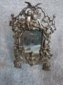A cast iron repousse design standing mirror with cherub motifs. H 37