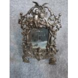 A cast iron repousse design standing mirror with cherub motifs. H 37