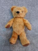 Antique yellow plush jointed Chad Valley growler teddy bear. Brown fabric pads and label to foot.