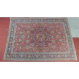 A Tabriz rug with repeating floral and petal motifs on a terracotta field encompassed with a