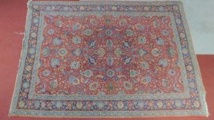 A Tabriz rug with repeating floral and petal motifs on a terracotta field encompassed with a