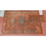 A Tabriz style rug with triple pendant medallion on a rouge field with repeating geometric