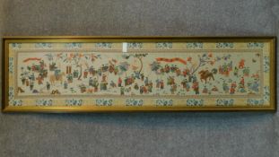 A large framed and glazed silk embroidery depicting a Chinese festival. 53x187cm