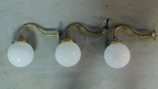 A set of three brass wall lamps with opaque glass spherical shades. H.26 D.29cm