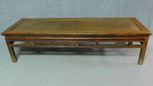 A Chinese teak low table with rattan inset top above carved frieze on square section supports. H.