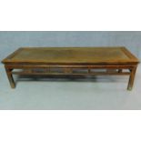 A Chinese teak low table with rattan inset top above carved frieze on square section supports. H.