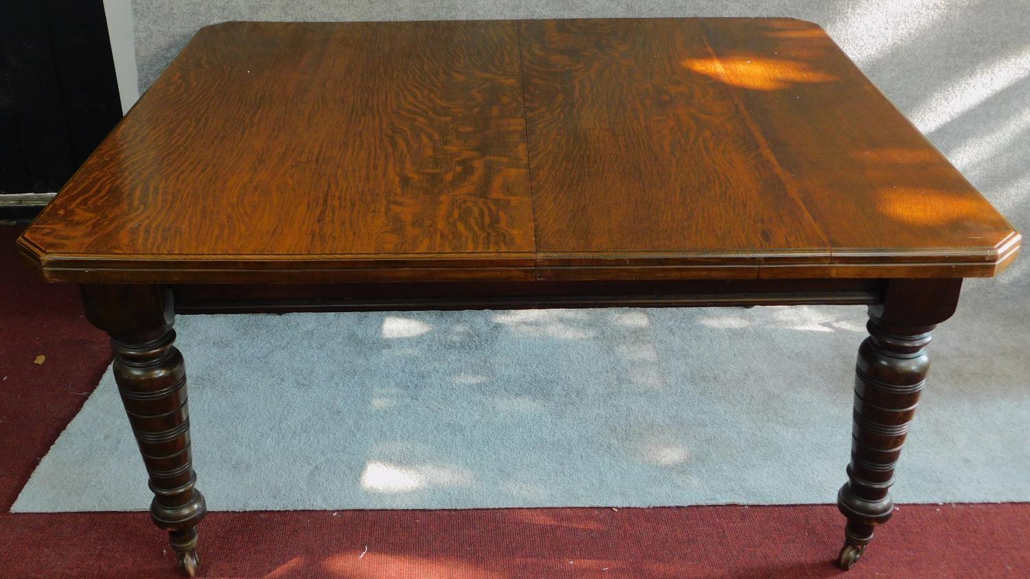 A late Victorian oak extending dining table with four extra leaves on turned tapering supports. H.75