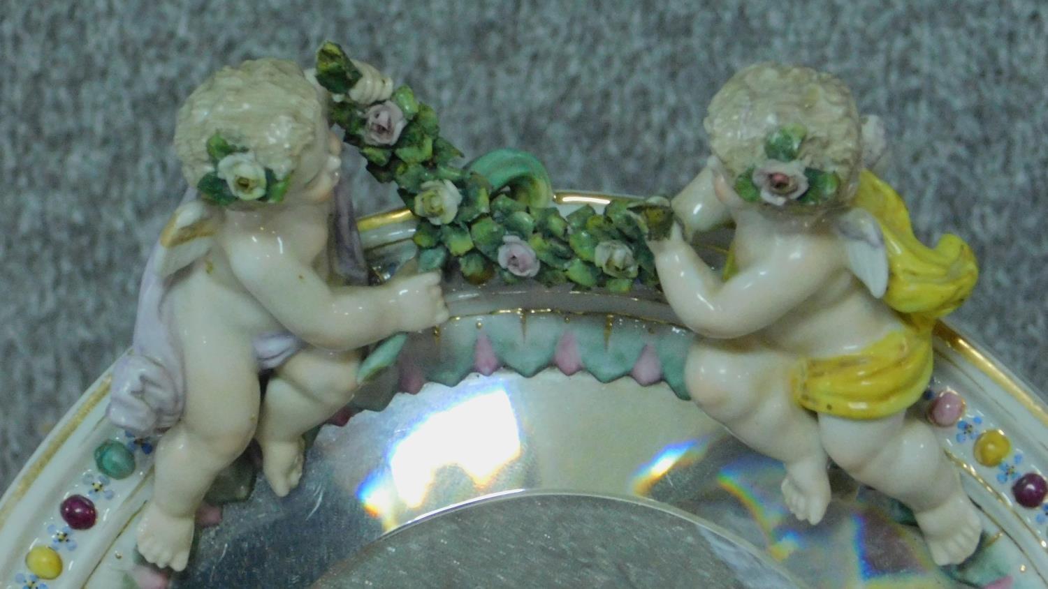 A 19th century porcelain framed German oval bevelled mirror with floral and cherub decoration, by - Image 2 of 5