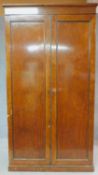 An early 19th century plum pudding mahogany hall cupboard fitted with panel doors enclosing