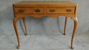 An early 20th century satin walnut Queen Anne style two drawer writing desk on cabriole supports.