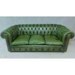 A three seater Chesterfield sofa in green leather buttoned upholstery. H.76 W.207 D.96cm