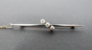 A 3 stone diamond cross over bar brooch, set with three round old cut diamonds in openback claw