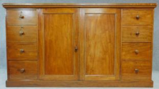 A mid 19th century mahogany press cupboard fitted central section with panel doors enclosing linen