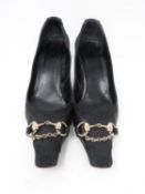 A pair of GUCCI stiletto heels, with gold stirrup and chain detailing on the front. GUCCI print