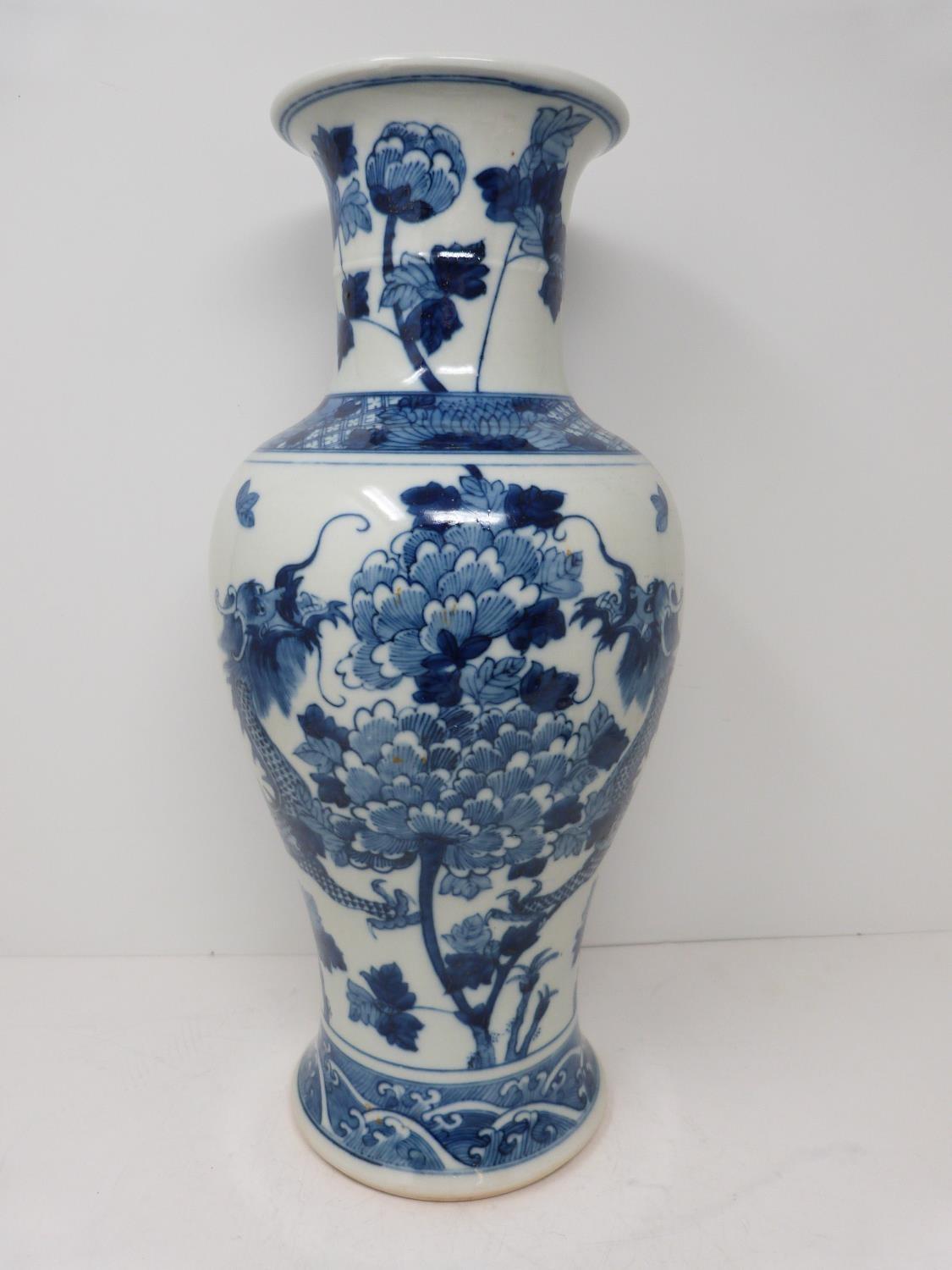 A Kangxi style blue and white baluster dragon vase with floral motifs. Four character mark to