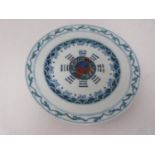 A Doucai style saucer dish with central yin-yang motif and stylized wave and scale design. Six
