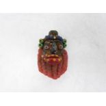 A Phoenician glass face pendant. In the form of an old man with large red lips and beard. Hanging