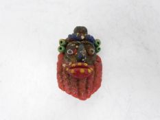 A Phoenician glass face pendant. In the form of an old man with large red lips and beard. Hanging