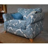 A large armchair with blue patterned fabric upholstery and two scatter cushions. H. 94 x 120 x 94cm