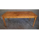 A large pine kitchen dining table on turned tapering supports. L.183 x H.75cm