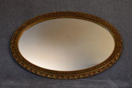 A gilt framed oval wall mirror with gadrooned and floral edging. L.115cm x 75cm.