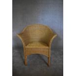 A wicker tub shaped conservatory armchair. H. 80 x 70cm