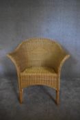 A wicker tub shaped conservatory armchair. H. 80 x 70cm