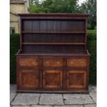 An antique oak dresser with plate rack above three frieze drawers and panel doors on plinth base.