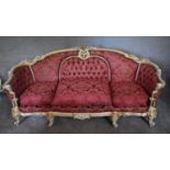 A large gilt and painted framed Rococo style three seater sofa, upholstered in burgundy damask