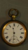 An antique brass pocket watch with bevelled glass and white enamel dial with black Roman numerals,