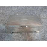 A silver cigarette box with engine turned decoration and two plain rectangular cartouches.