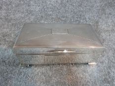 A silver cigarette box with engine turned decoration and two plain rectangular cartouches.