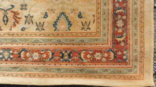A Persian style rug with repeating floral motifs on a yellow field surrounded by floral and