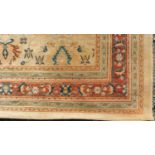 A Persian style rug with repeating floral motifs on a yellow field surrounded by floral and