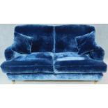 A Howard style blue velvet sofa raised on turned supports with casters. H.90 W.180 D.100cm