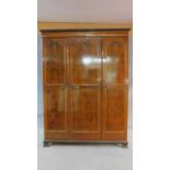 A mid 20th century Queen Anne style burr walnut triple door wardrobe with gilded floral carving