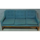 A mid 20th century teak framed sofa upholstered in turquoise raised on stretchered square