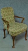 An early Georgian style walnut armchair with floral upholstery and raised on shell motif carved