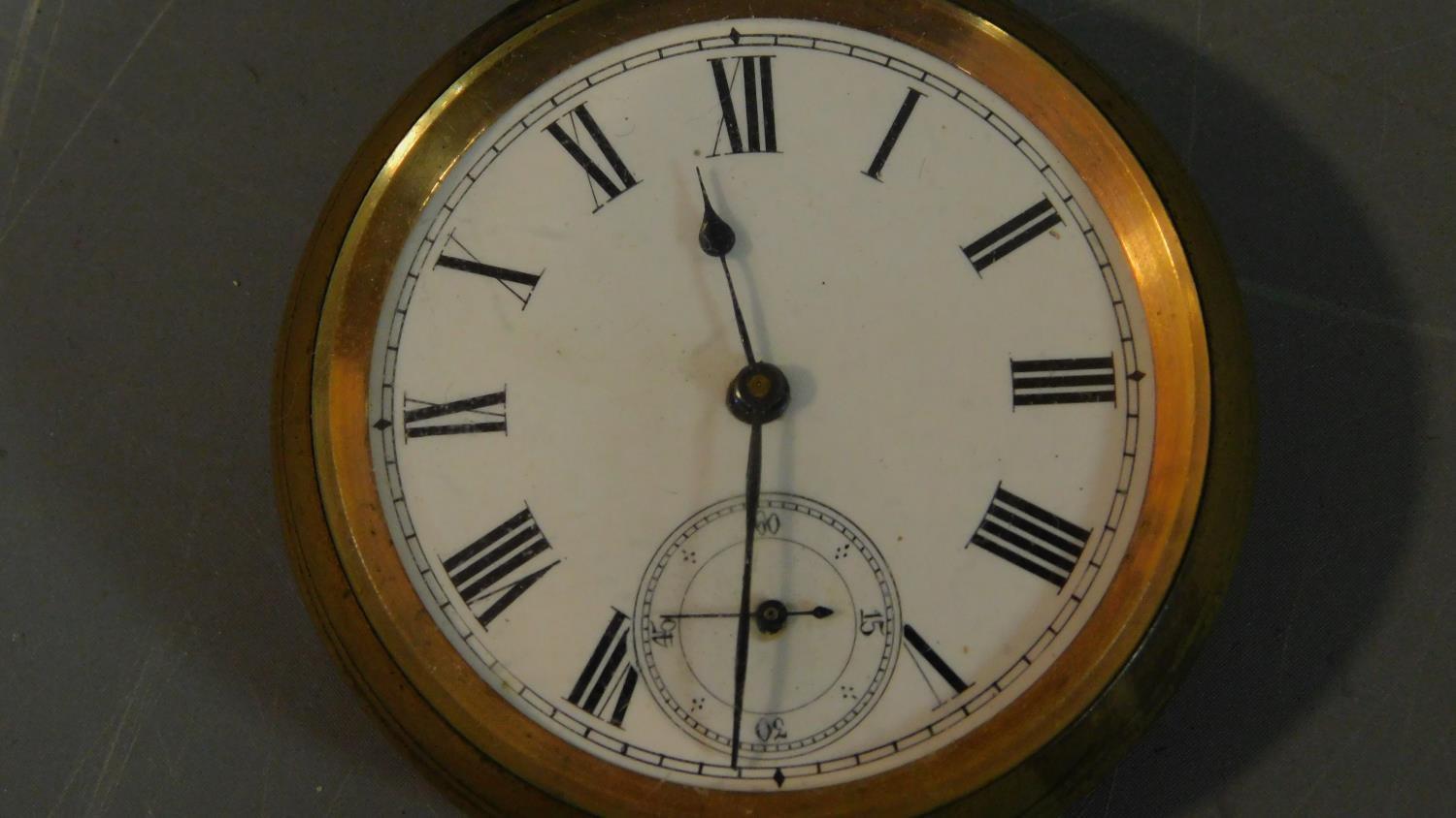 An antique brass pocket watch with bevelled glass and white enamel dial with black Roman numerals, - Image 2 of 9