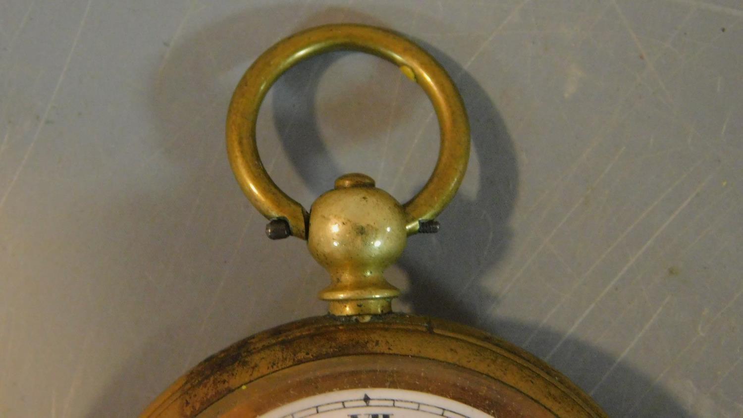 An antique brass pocket watch with bevelled glass and white enamel dial with black Roman numerals, - Image 8 of 9