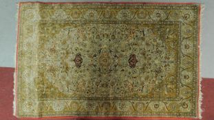 A Persian rug with floral medallion surrounded by floral motifs, swags and spandrels on a yellow