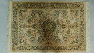 A Persian style rug with central pendant medallion on an ivory and green field with repeating floral